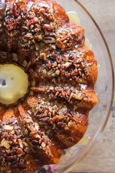 a bundt cake sitting on top of a glass plate covered in nuts and butter