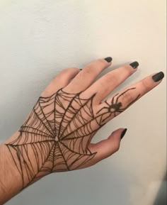 a woman's hand with a spider web design on it, and black nails