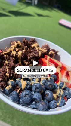 a white bowl filled with blueberries, strawberries and crumbled oats