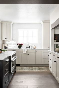 a large kitchen with white cabinets and black counter tops, along with wooden flooring