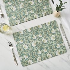 two placemats with flowers on them next to silverware and utensils