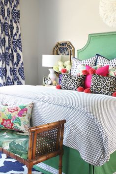 a green bed with colorful pillows on it and a chair in front of the bed