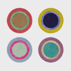 four woven coasters with different colors on them