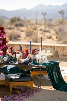 a table set up with flowers and candles for a wedding reception in the mountainside