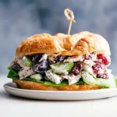 a chicken salad sandwich with cucumbers and cranberries on a white plate