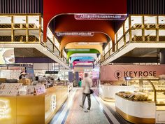 a person walking down a long hallway in a shopping mall with lots of food on display