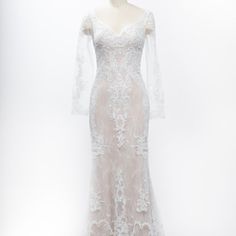 a white wedding dress with long sleeves and sheer lace on the shoulders, in front of a mannequin head