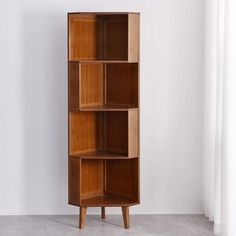 a tall wooden shelf with three shelves on each side, in front of a white wall