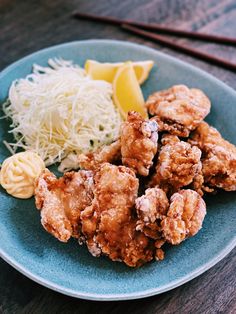 a blue plate topped with fried food next to noodles and grated parmesan cheese