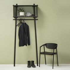 a coat rack and chair in front of a wall with an open jacket hanging on it