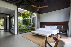 a bedroom with a large bed sitting next to a window covered in plants and greenery