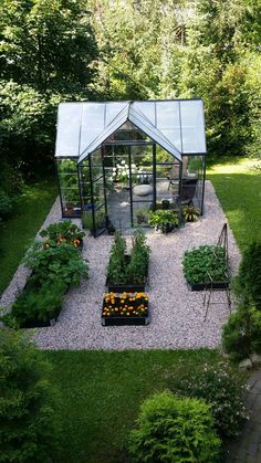 a small garden with lots of plants and flowers in the center, surrounded by gravel