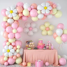 a table topped with balloons and cake next to a wall