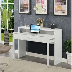 a white desk with a laptop on it in front of two pictures and a chair