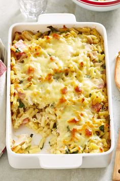 a casserole dish with chicken and noodles in it on a table next to bread