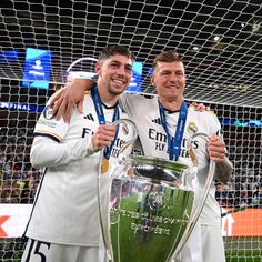 two soccer players are posing with the trophy