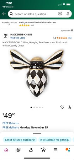 a black and white bee brooch sitting on top of a green phone case next to an amazon gift card