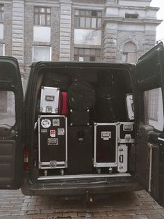 the back end of a blue van with its doors open and various equipment in it