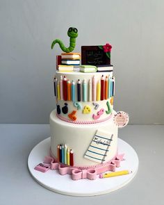 a three tiered cake decorated with crayons, books, and pencils