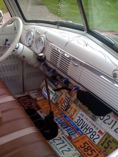 the interior of an old car with license plates on the floor and steering wheel,