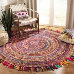 a room with a chair and rug on the floor next to a potted plant