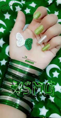 a person's hand with green and white nail polish on it, while the other hand has four clovers painted on them