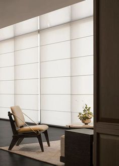 a chair sitting on top of a wooden floor next to a window covered in blinds