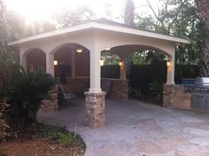 a covered patio with an outdoor grill and seating area