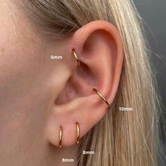 a woman's ear is shown with two small gold hoops