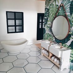 a bathroom with a sink, mirror and bathtub in front of a tropical wallpaper