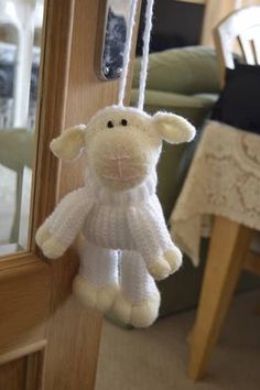 a white stuffed animal hanging from a door handle next to a table with a chair in the background