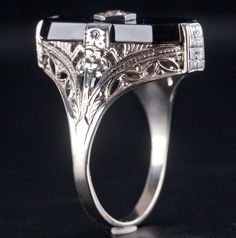 a close up view of a ring on a black surface with an intricate design and diamond accents