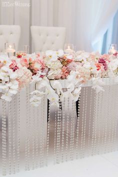 a long table with flowers and candles on it is set up for a wedding reception