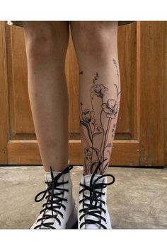 a woman's legs with flowers on them and black laces around the ankles