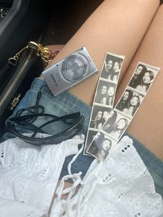 a woman's legs with pictures and a camera on top of them, next to her purse