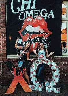 two girls standing in front of a sign with the word xo and lips painted on it