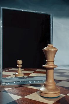 a wooden chess set sitting on top of a checkerboard floor next to a mirror