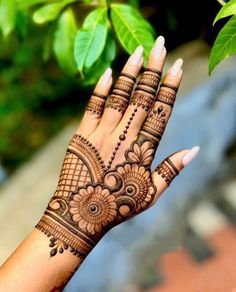 a woman's hand with hennap on it and green leaves in the background