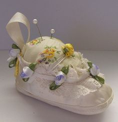 there is a white shoe with flowers on it and some pins sticking out of the top