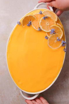 two hands holding a yellow cake with lemons and blue flowers