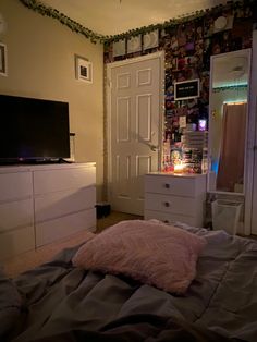 a bedroom with a bed, dresser and television on the wall in front of it