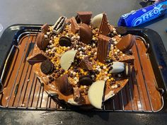 a chocolate cake with candy and other toppings on a cooling rack next to an oreo bar