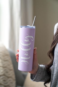 a woman holding a purple tumbler with the word hello kitty on it and a straw in her hand