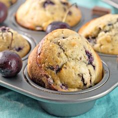 blueberry muffins in a metal pan with fresh cherries on the side