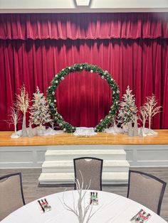 a christmas wreath sits in front of a stage decorated with trees and snowflakes