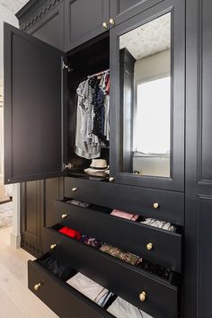 a closet with black cabinets and drawers filled with clothes, shoes and other items in it