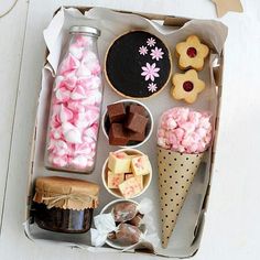 a tray filled with different types of desserts and candies on top of a white table