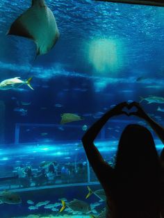 a woman standing in front of an aquarium looking at fish