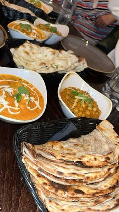 a table topped with lots of food on top of plates next to bowls filled with soup