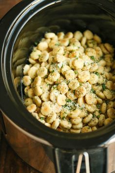 a crock pot filled with macaroni and cheese sitting on top of a wooden table